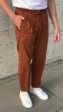 Laden Sie das Bild in den Galerie-Viewer, Side profile of rust seersucker trousers styled with brown suede loafers