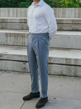 Load image into Gallery viewer, A man standing on outdoor steps wearing light blue pleated trousers  with side adjusters and a striped shirt.